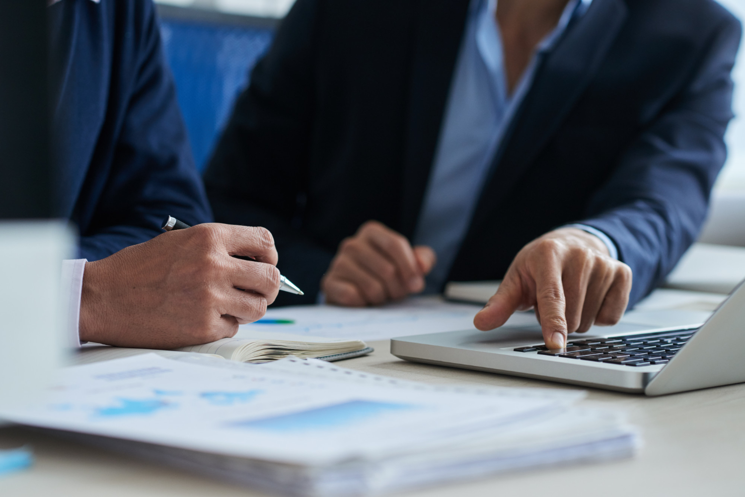 Profesionales trabajando con documentación financiera y un ordenador portátil